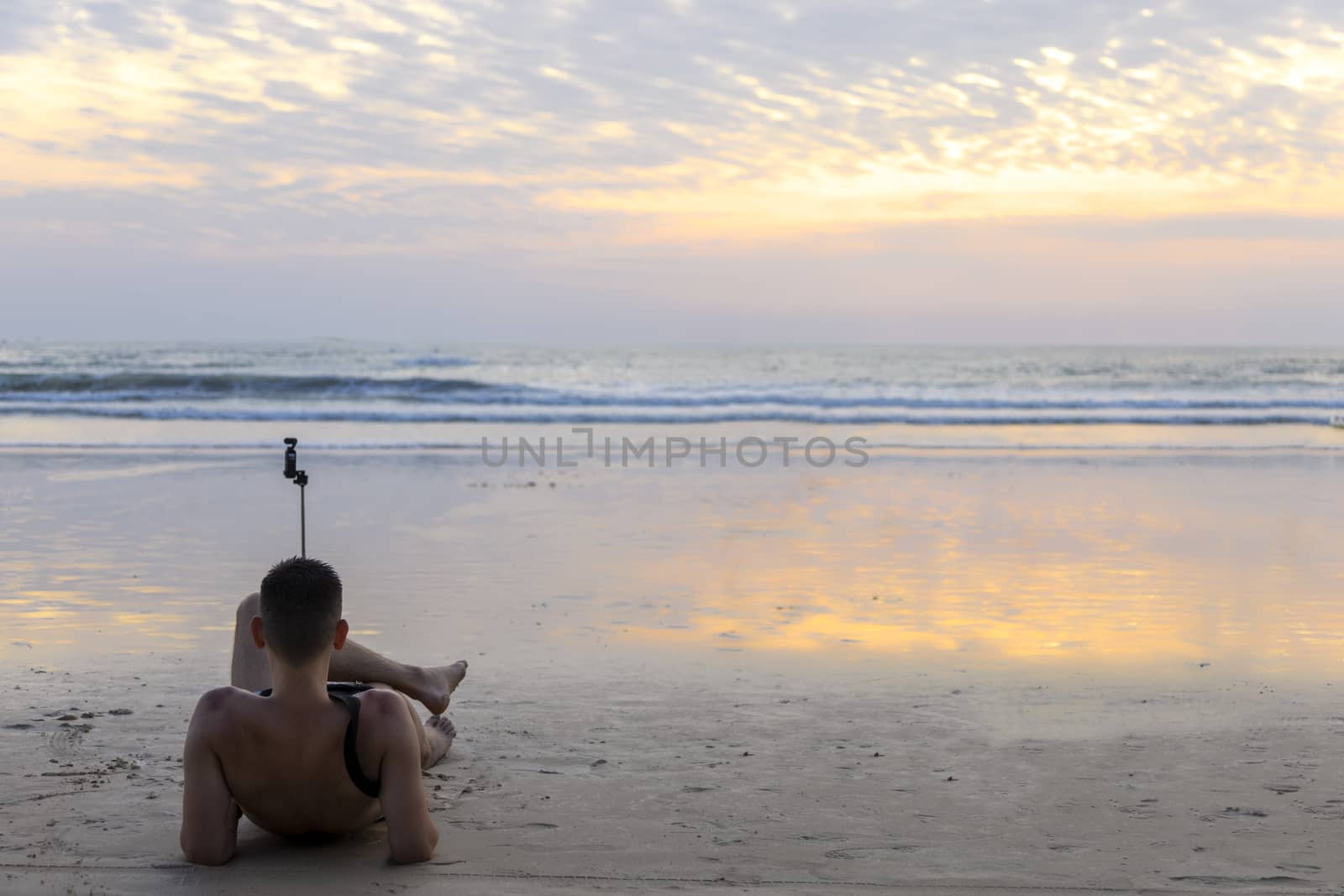 Man sitting with little camera on the beach relax and wait sunset time for shot a picture