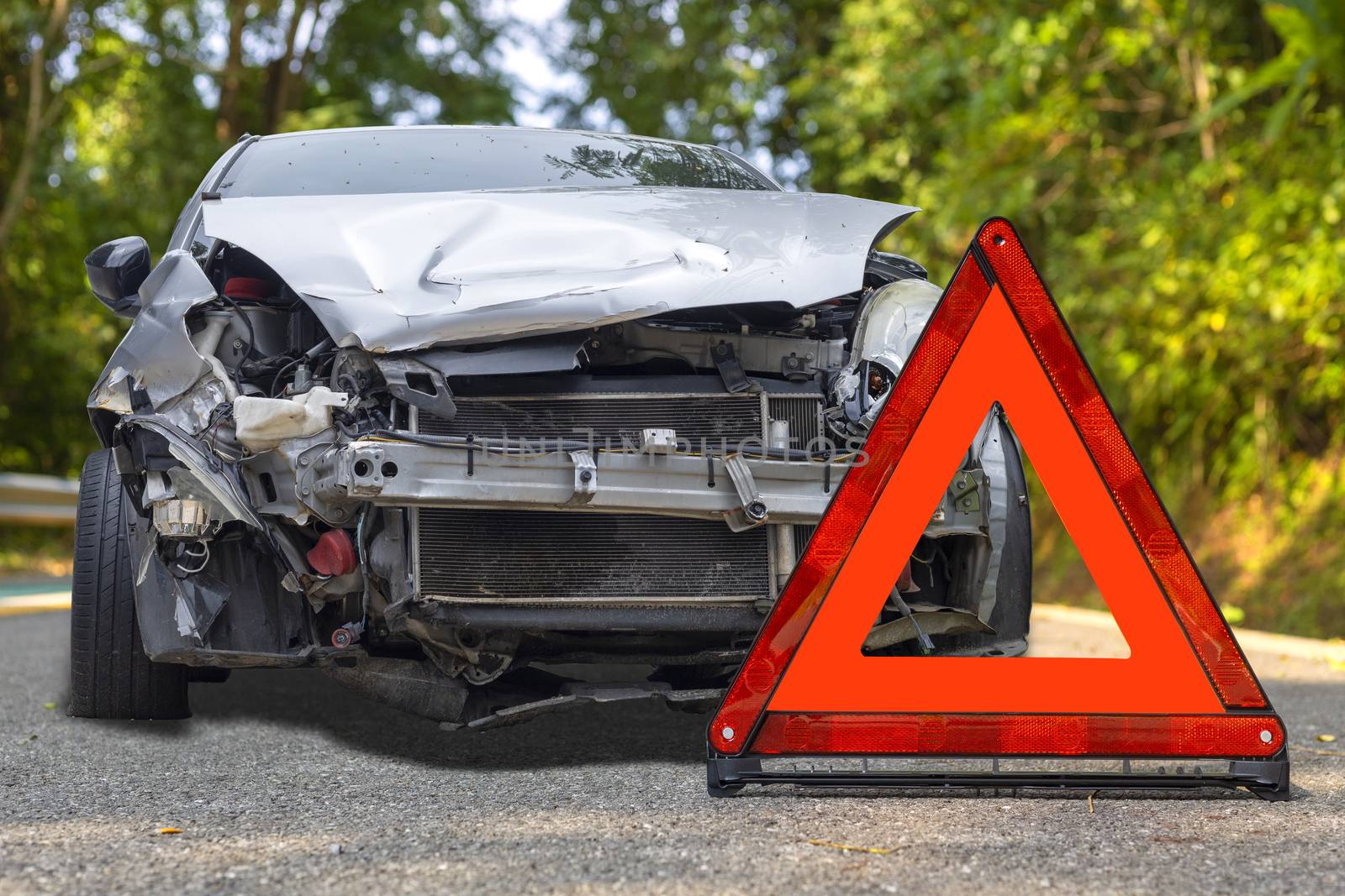 Front of gray color car big damaged and broken by accident on city street parking can not drive any more on road have red triangle sign for emergency warning. 