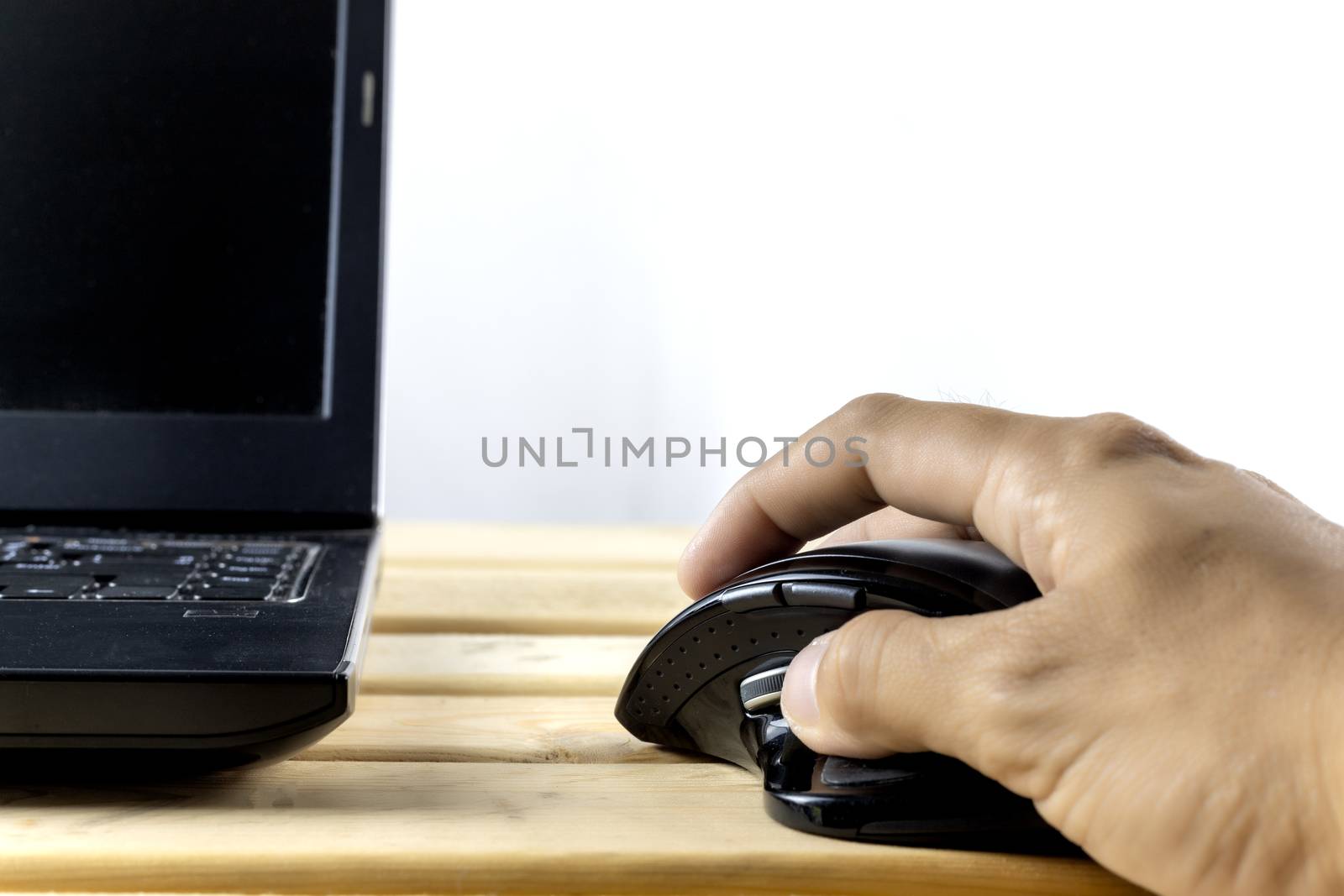 Hand hold mouse control laptop on wood table. With copy space for text or design.