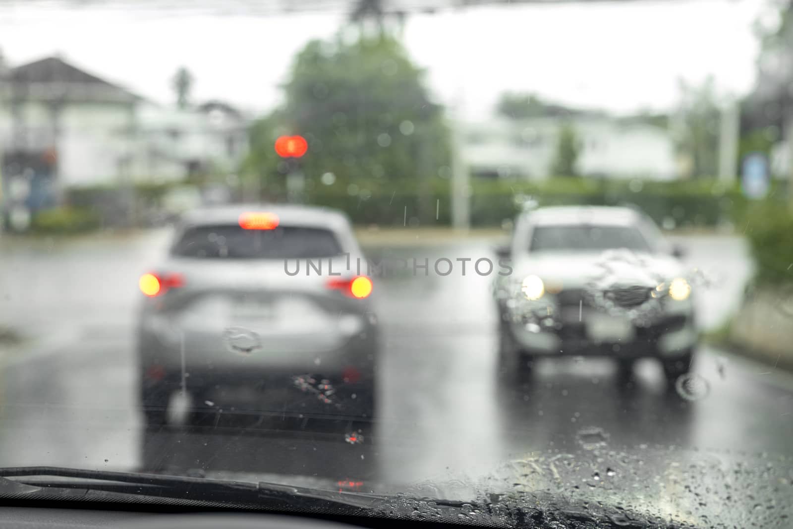 drive a car on the road stop witn trafic light with raindrop over the wind shield. Shot form wind shield