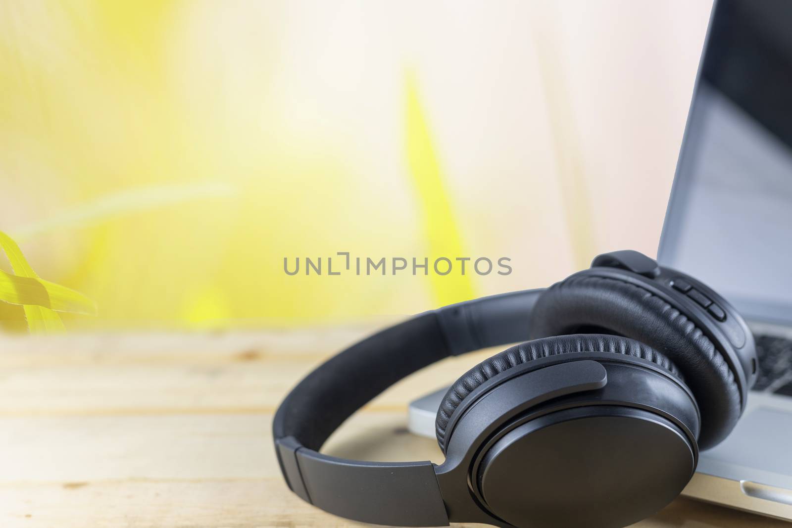 Wriless headphones and laptop on wood table in garden. With copy space for text or design. Technology concept.