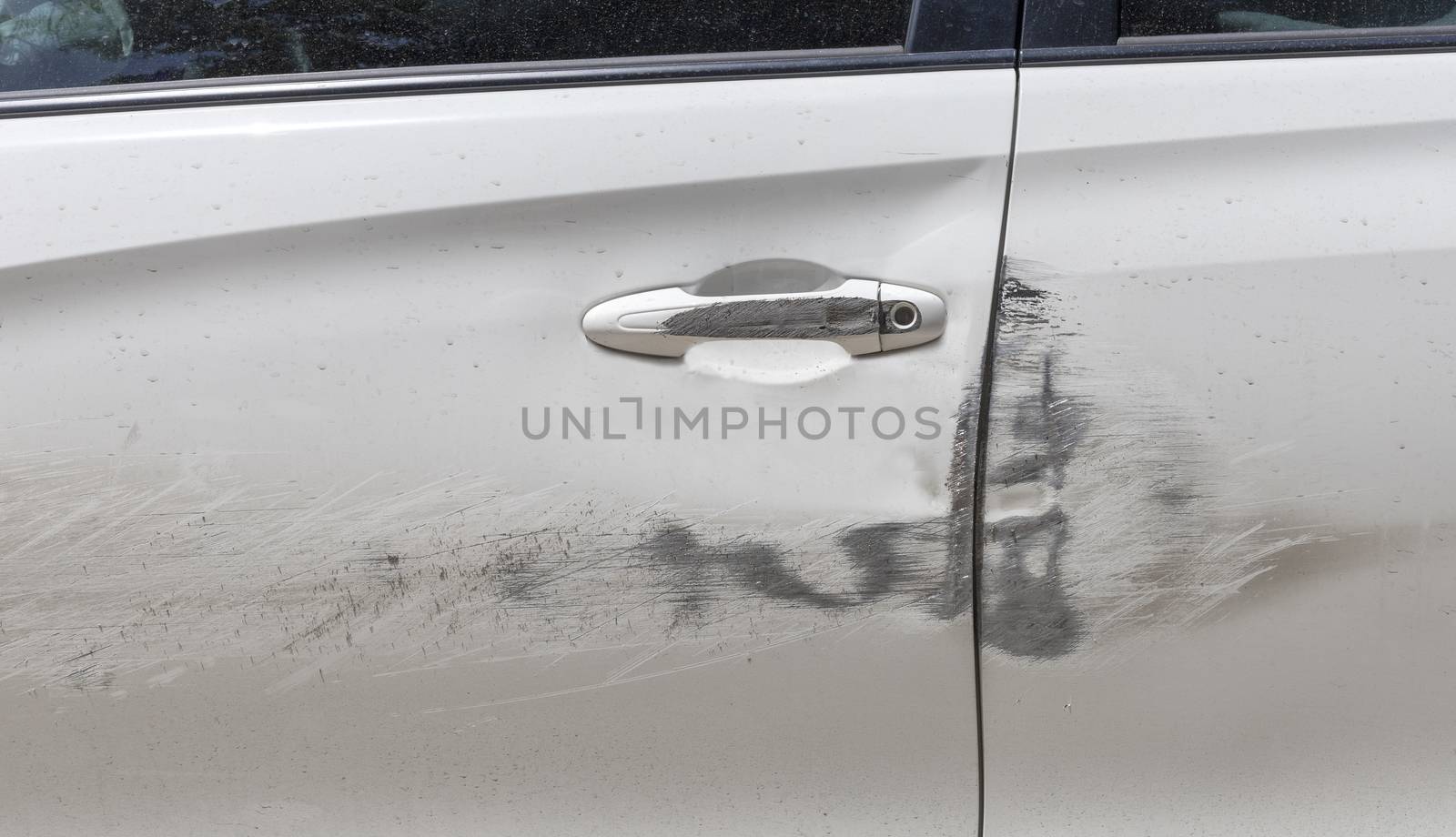 Car door handle and white car door have scratches from damaged by accident