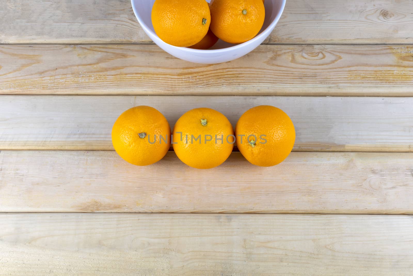 Top view Fresh oranges in white bowl on wood table. With copy space for text or design.