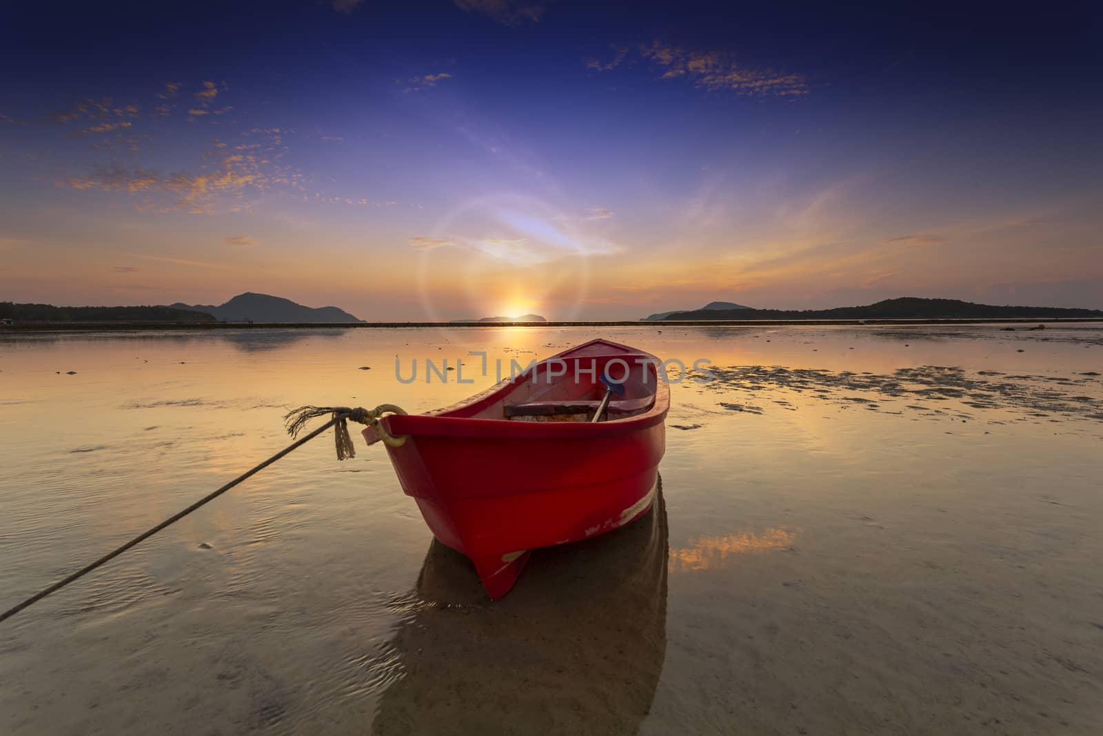 Sunrise morning time alone red fishing boat on the beach and low tide sea background.