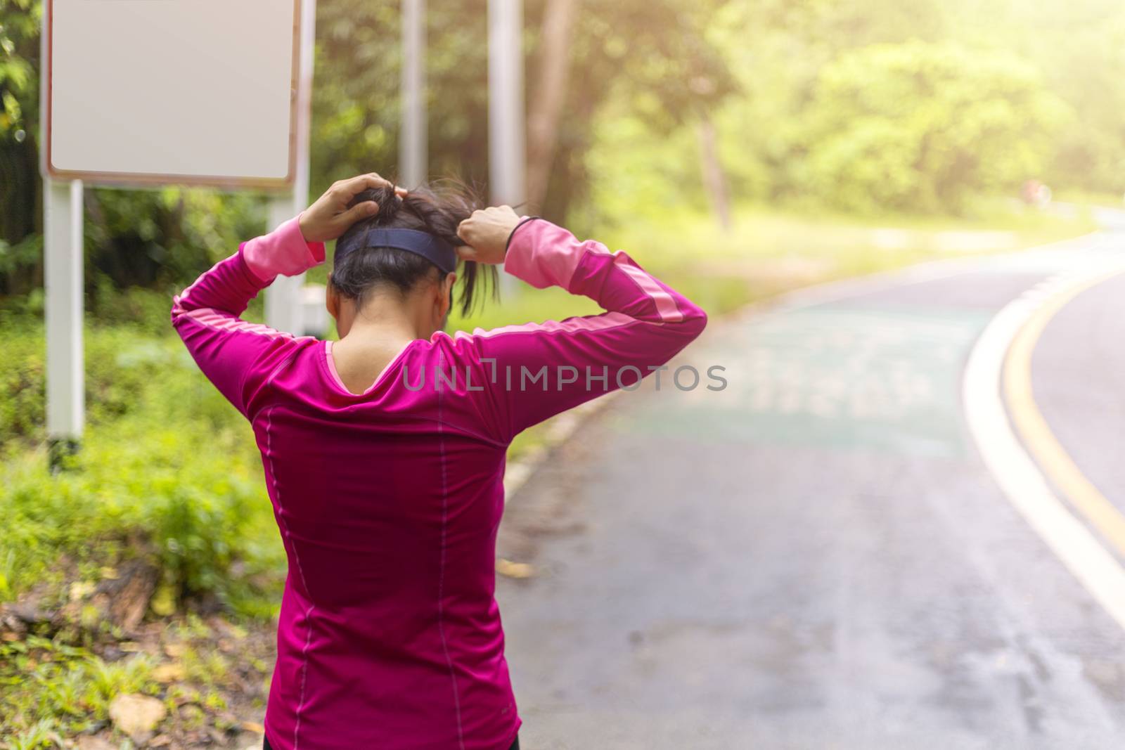 Women with pink long sleeve tied her hair before runing on road in morning time.