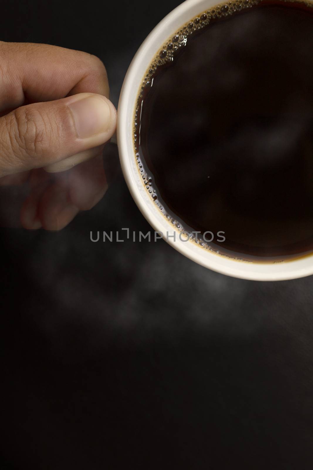 Top view hand man hold the white coffee cup wiht hot black coffee in side. With copy space for text or desing