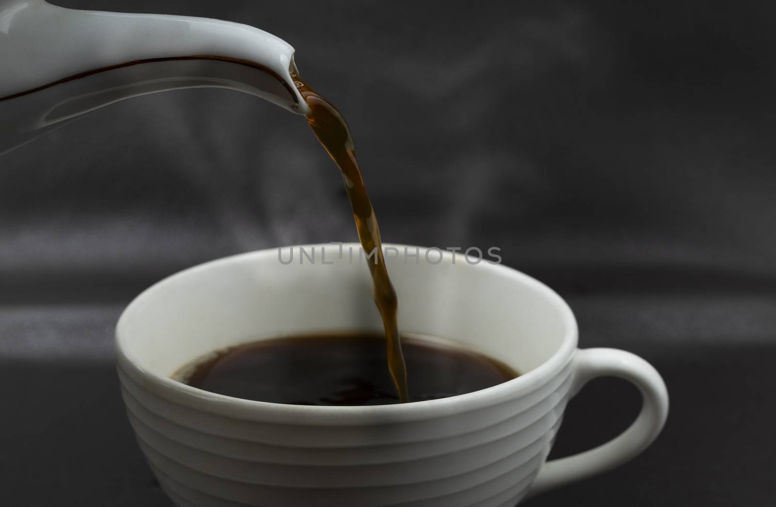 Close up pouring the black coffee from pot into cup