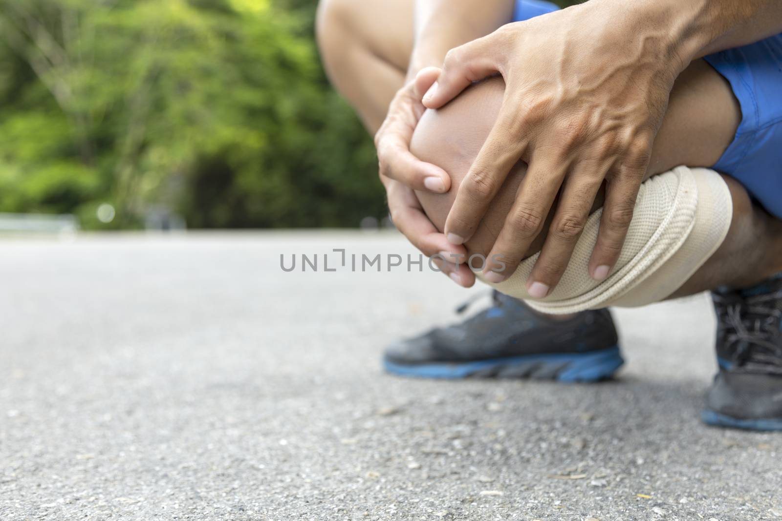 Man use hands hold on his knee after running on road in morning 