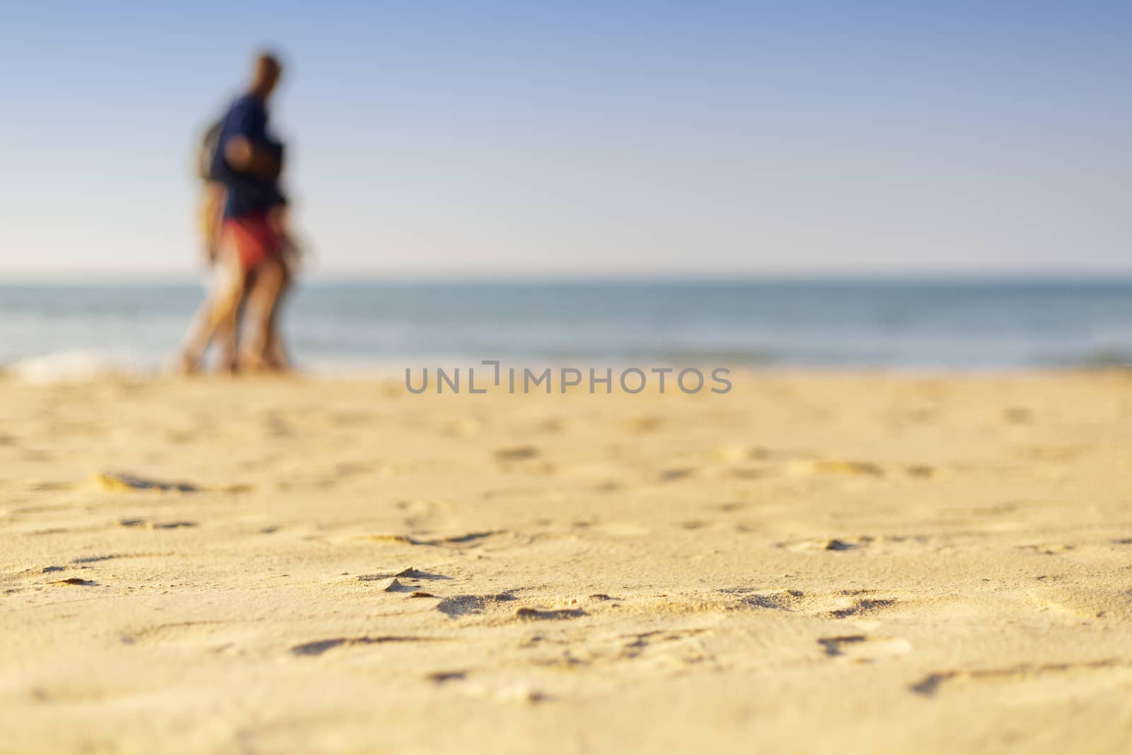 Holiday concept. Clear sand with blur guy, sea and clear sky background. Soft focus and focus selective sand.