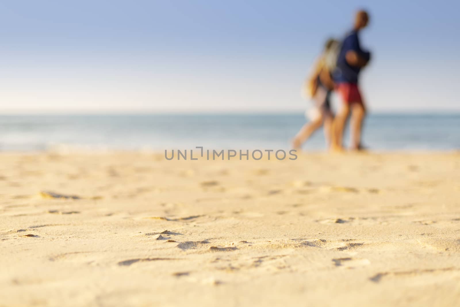 Holiday concept. Clear sand with blur guy, sea and clear sky background. Soft focus and focus selective sand.