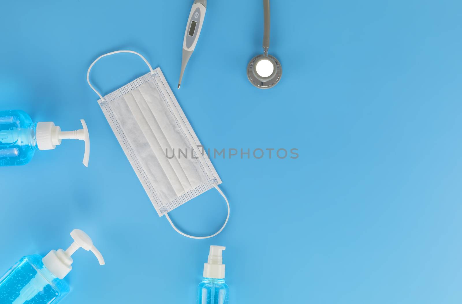 Top view Hygienic masks digital thermometer, Stethoscope , alcohol spray on blue background. Medical face mask, alcohol sanitizer, thermometer on blue background with copy space.