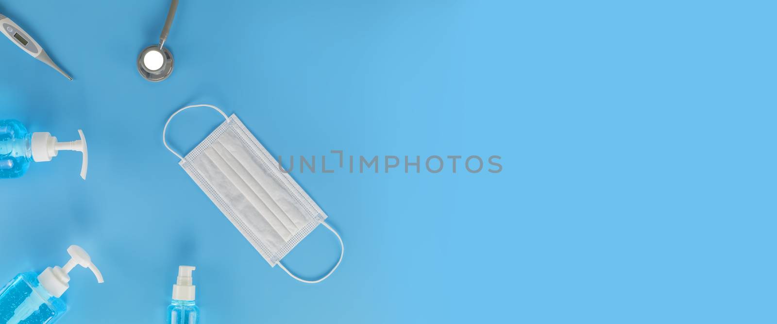 Top view Hygienic masks digital thermometer, Stethoscope , alcohol spray on blue background. Medical face mask, alcohol sanitizer, thermometer on blue background with copy space.