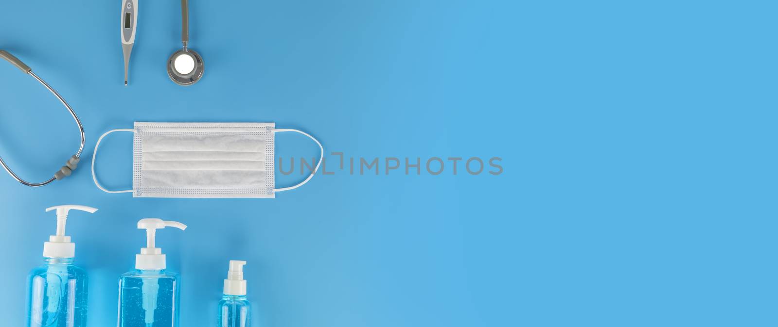 Top view Hygienic masks digital thermometer, Stethoscope , alcohol spray on blue background. Medical face mask, alcohol sanitizer, thermometer on blue background with copy space.