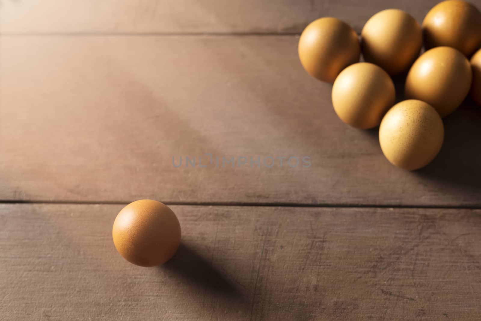 social distancing concept. Checken eggs have one chicken egg is far away from the group of chicken eggs.
Interpret social distancing. One and group for chicken eggs on wood table with copy space for text or design.Soft focus and focus selective alone egg.