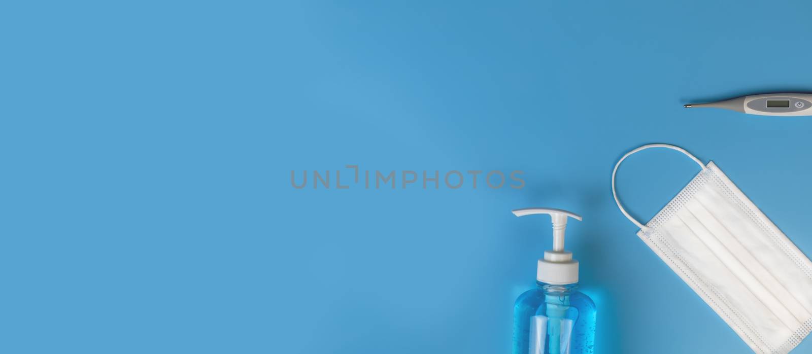 Top view Hygienic masks digital thermometer , alcohol spray on blue background. Medical face mask, alcohol sanitizer, thermometer on blue background with copy space.
