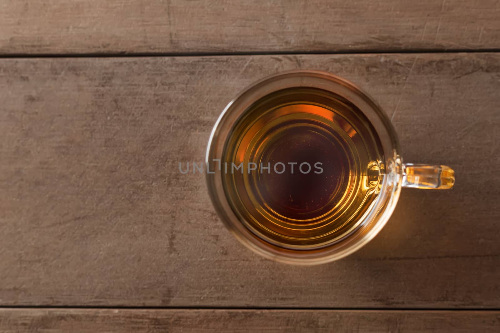 Close up top view hot tea cup on wood table . hot tea in handle glass with copy space for text or design.