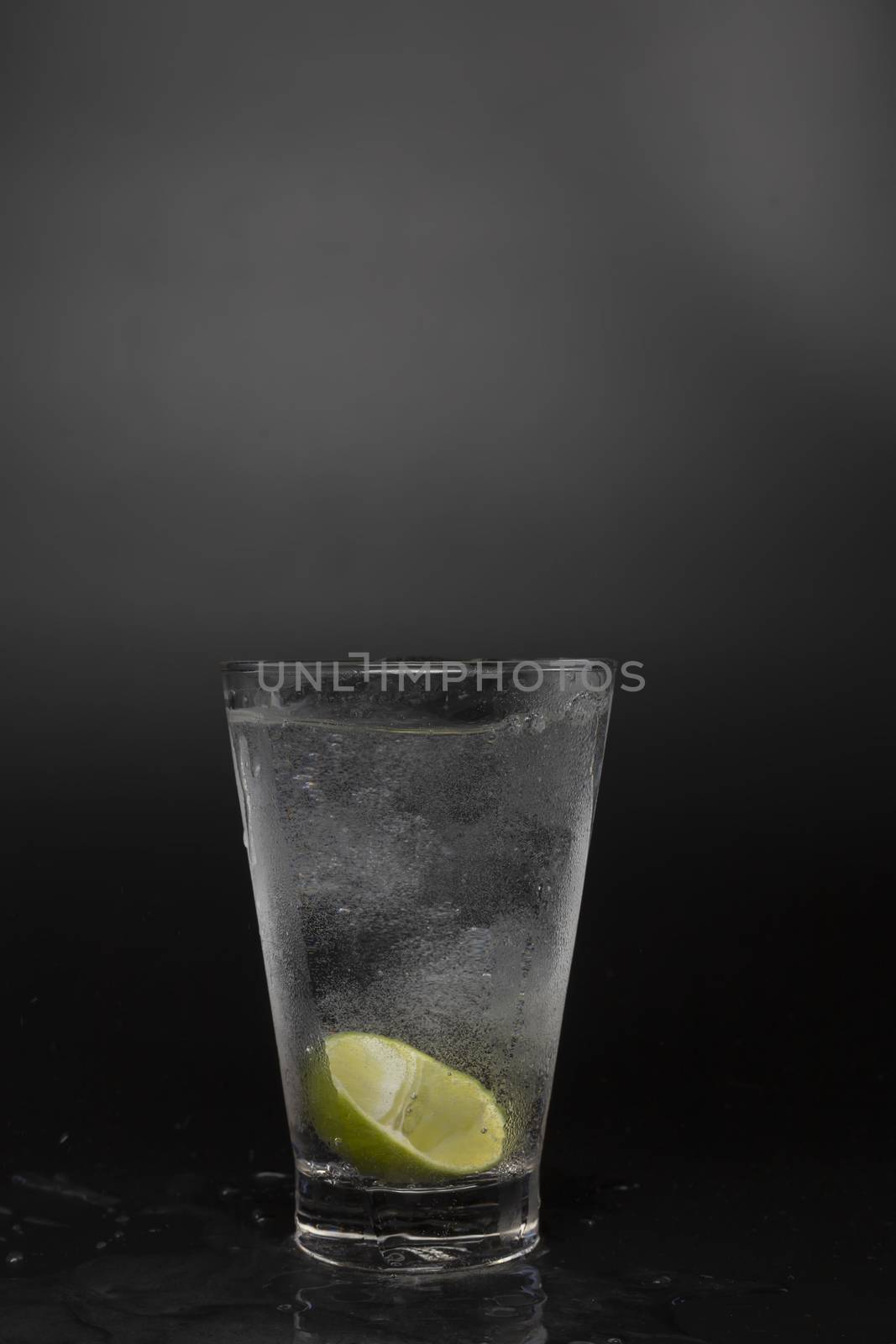 Soad water in glass with lime on black background. cool soda water and lime with copy space.
