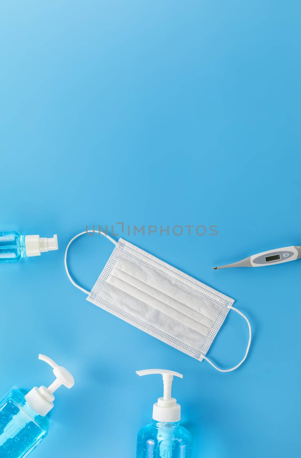 Top view Hygienic masks digital thermometer , alcohol spray on blue background. Medical face mask, alcohol sanitizer, thermometer on blue background with copy space.