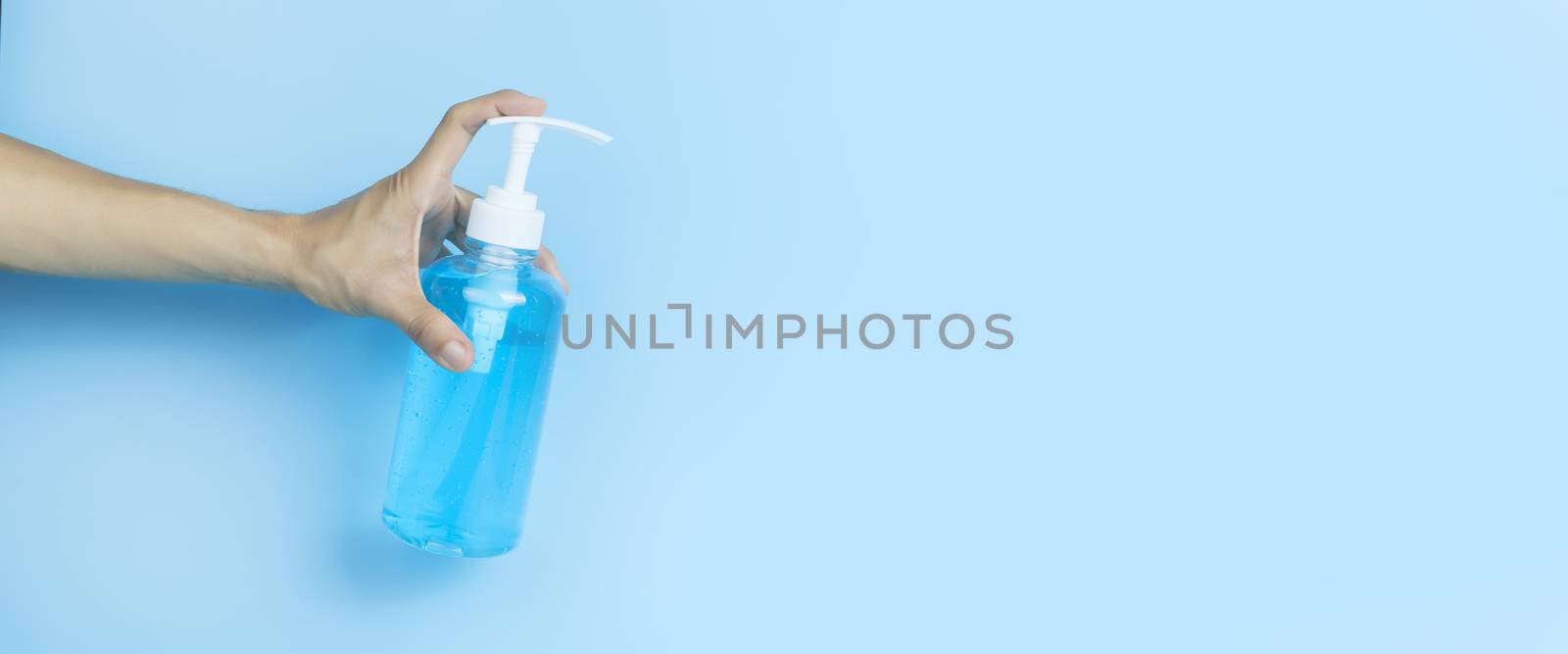 Hand holding alcohol gel. Hand holding alcohol gel sanitizer. Women hand holding alcohol gel sanitizer in pump head bottle on light blue background . With copy space.