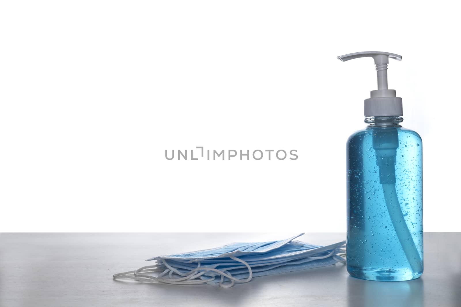 Face mask with alcohol sanitizer gel hand wash on wood table and white background with copyspace for text or design.