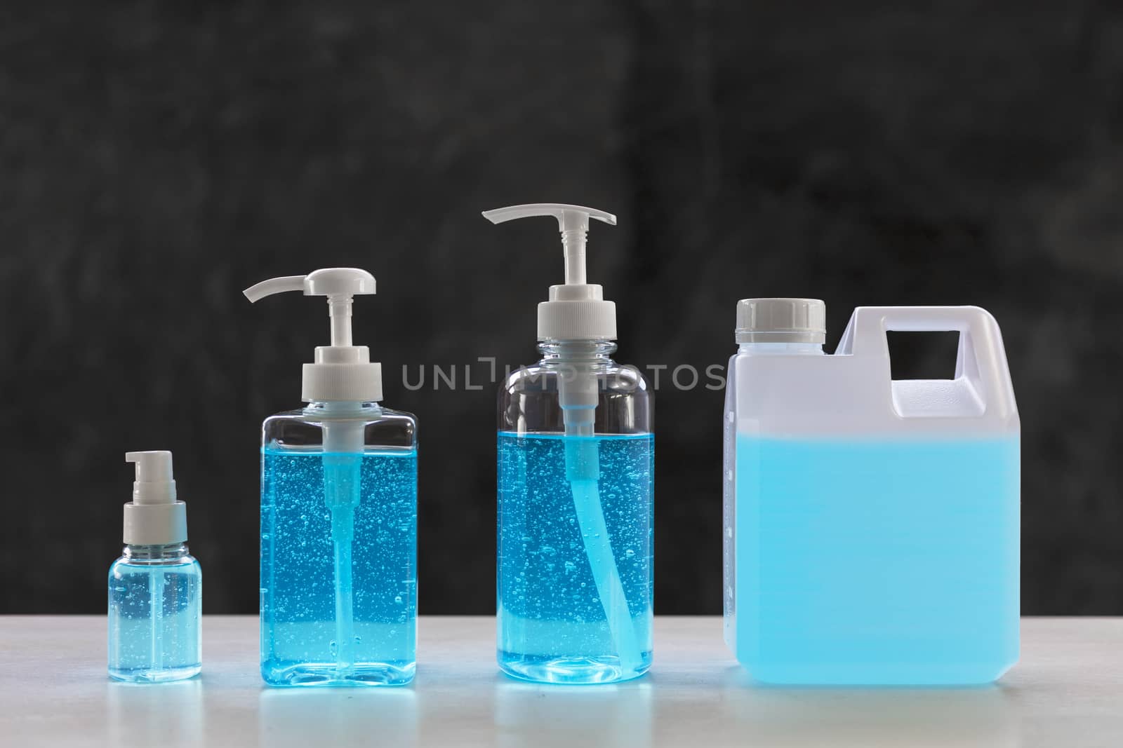 Blue alcohols gel on white table and  calcium oxide background. Hand sanitizer gel for clean. Hand sanitizer in 3 different size dump bottle. and 1L. bottle.