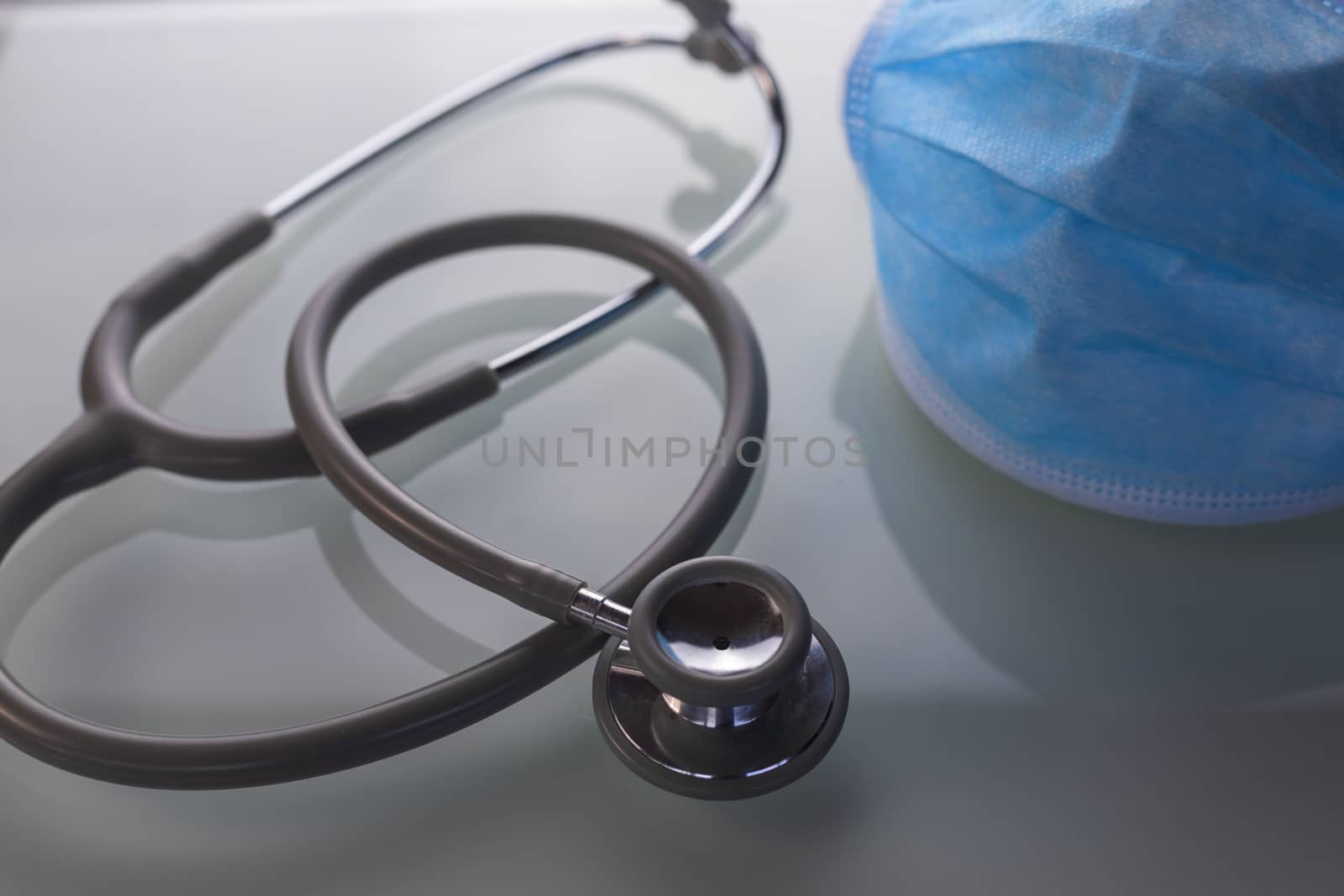 Stethoscope with medical mask on glass table. . Healthcare and medical concept. Blur focus and selective focus to head Stethoscope and medical mask