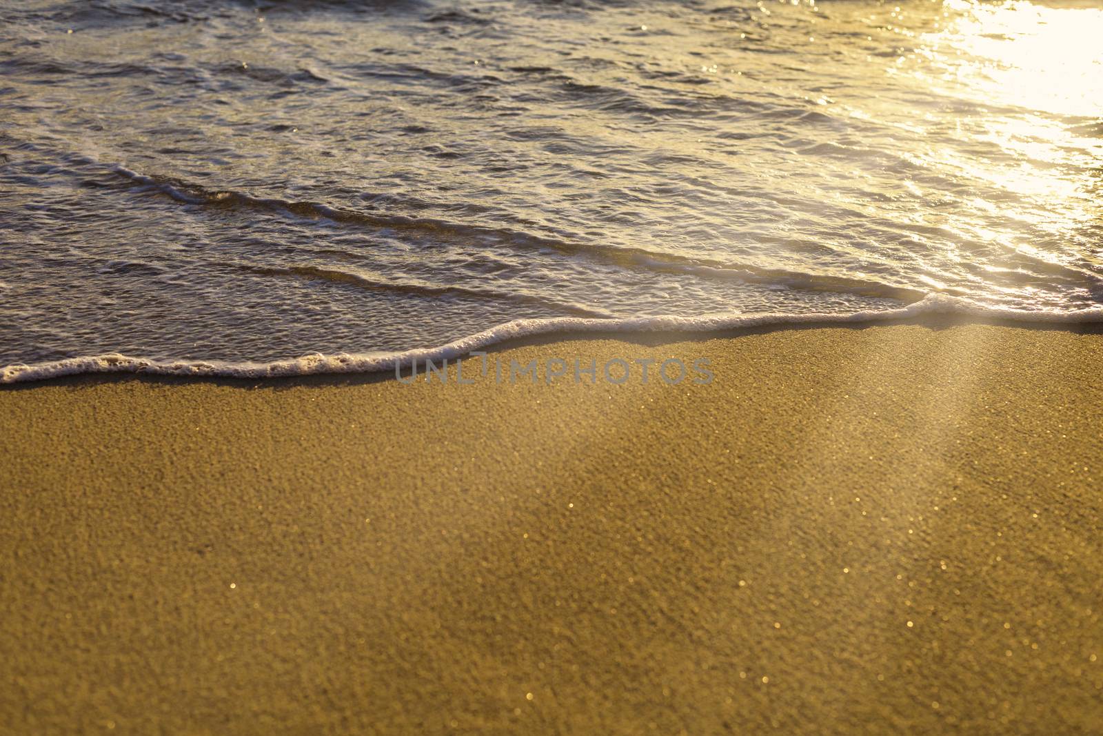 Soft wave from sea come to wet sand beach and sun ray background. With copy space for text or design. Beach background.