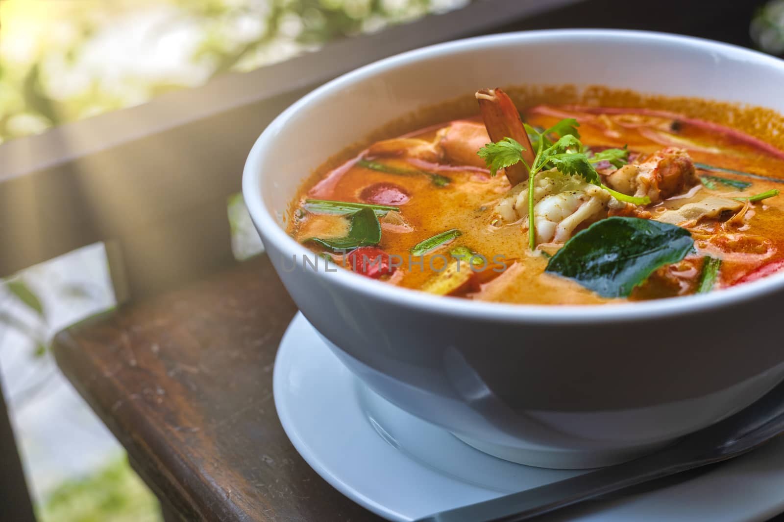 Tom Yam kung Spicy Thai soup with shrimp in white bowl on wood table. With copy space for text or design.
