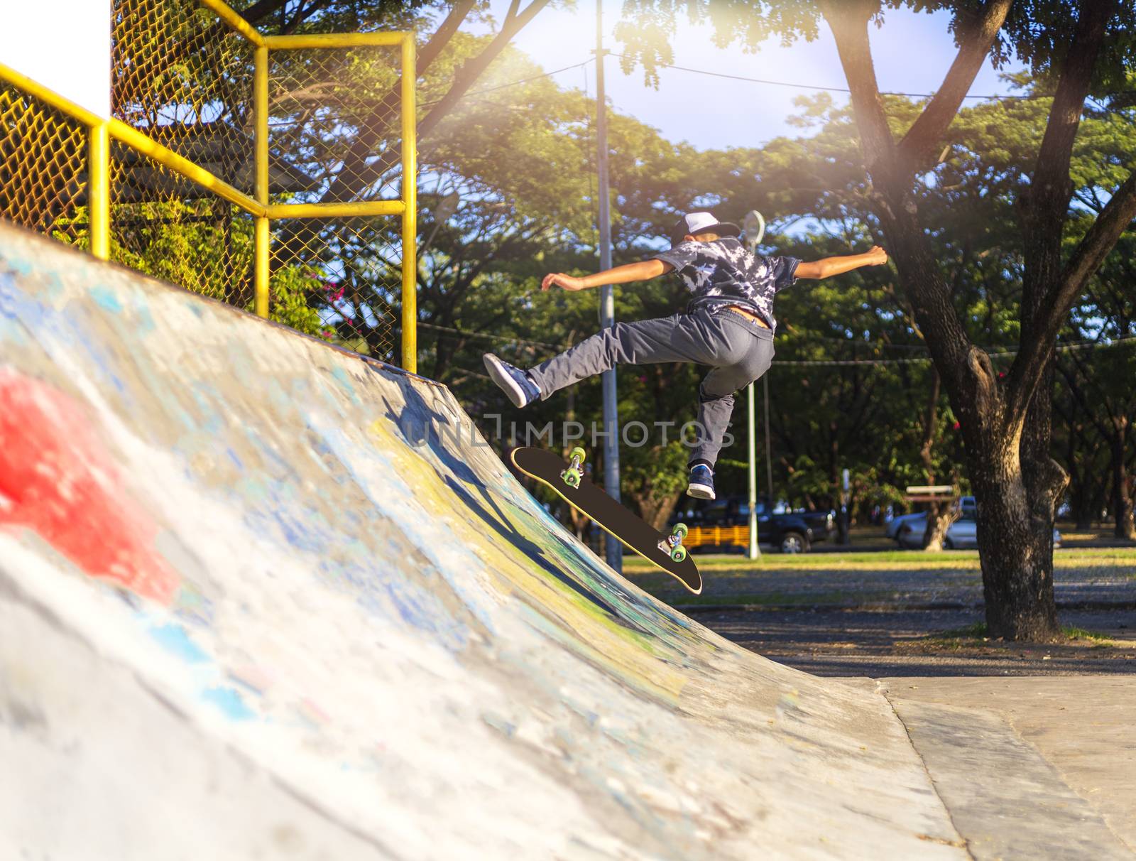 Young boy jump on ramp with skateboard outdoor.