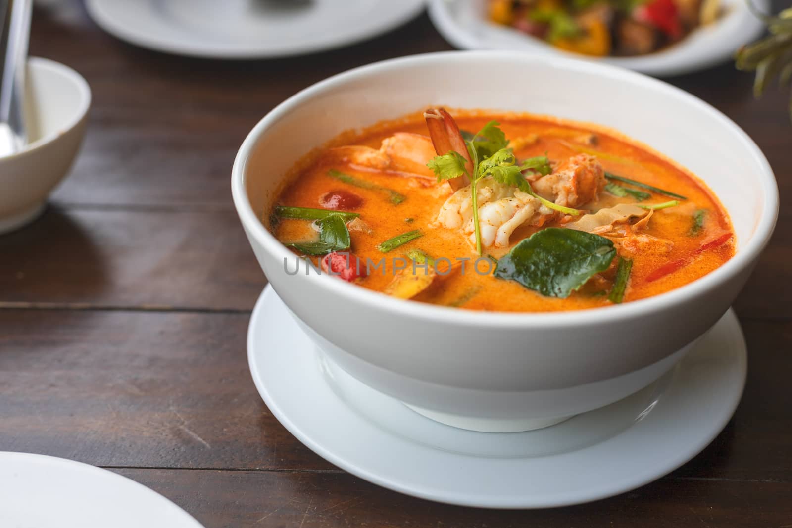Tom Yam kung Spicy Thai soup with shrimp in white bowl on wood table. With copy space for text or design.