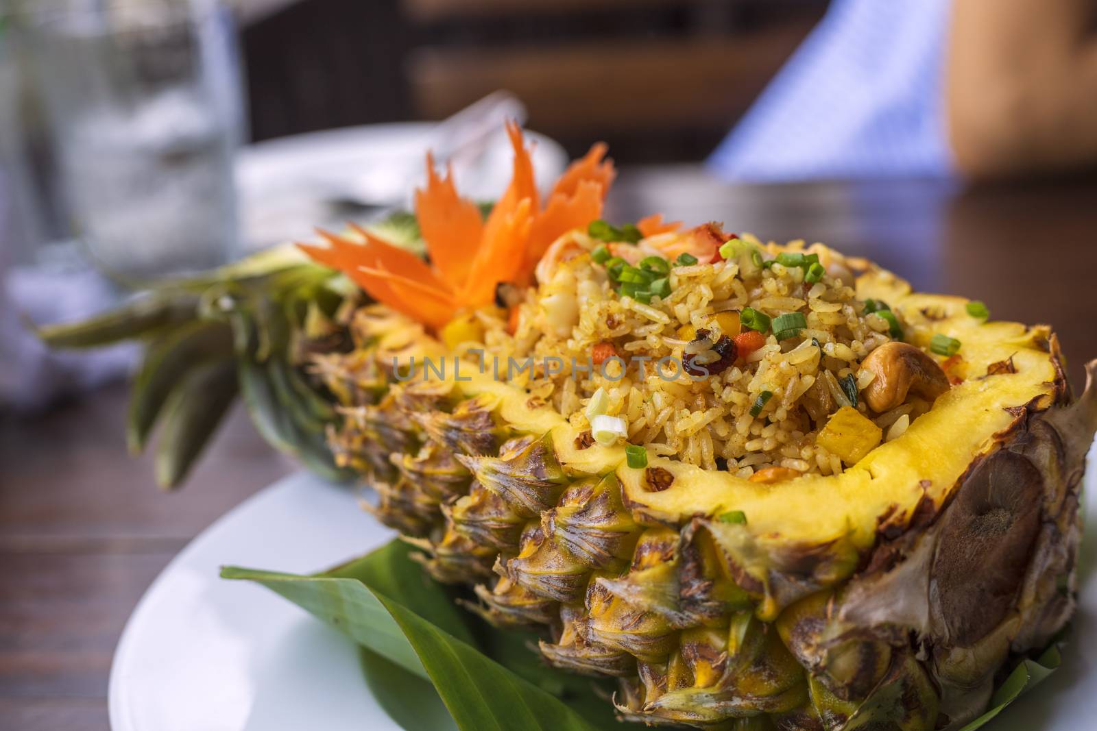 Thai royal pineapple fried rice. Fried rice with shrimps served in a pineapple on wood table.