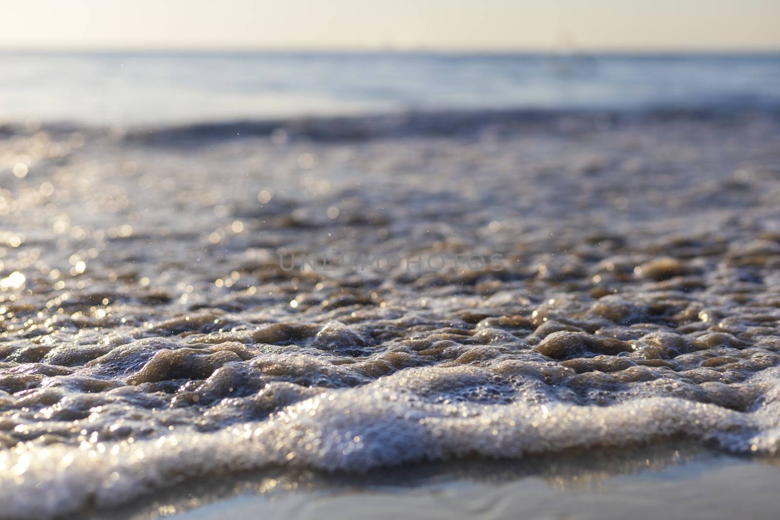 Soft wave from sea come to wet sand beach with blur clear sky background. With copy space for text or design