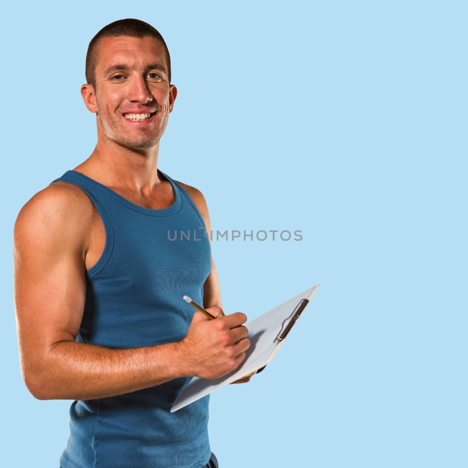 Portrait of confident sports coach writing on clipboard against blue background