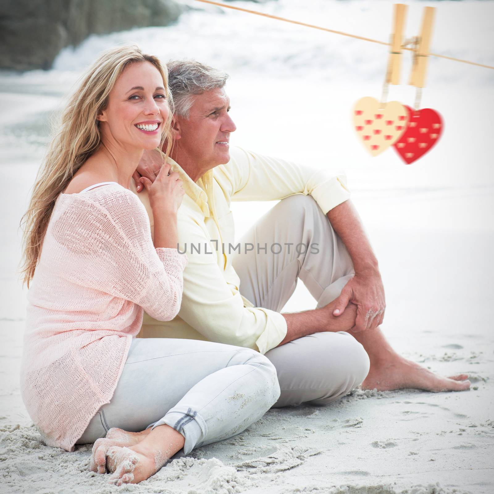 Composite image of happy couple sitting on the sand by Wavebreakmedia