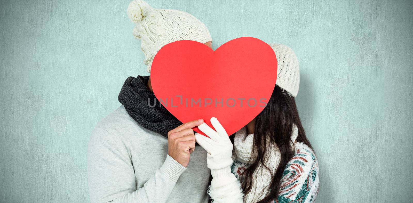 Smiling couple holding paper heart against blue background