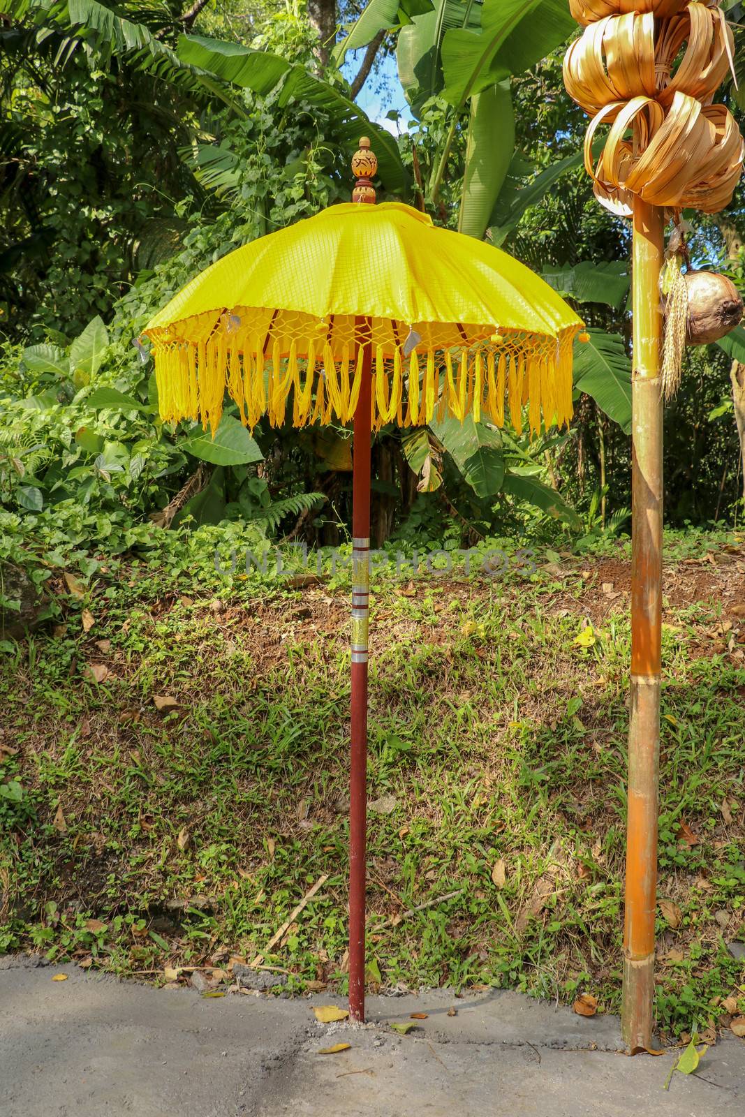 Decoration of Hindu temple complex Batukaru on Bali island in Indonesia. Yellow and white decorative umbrellas line the path for believing visitors. Colorful fabric umbrellas with decorative fringes.