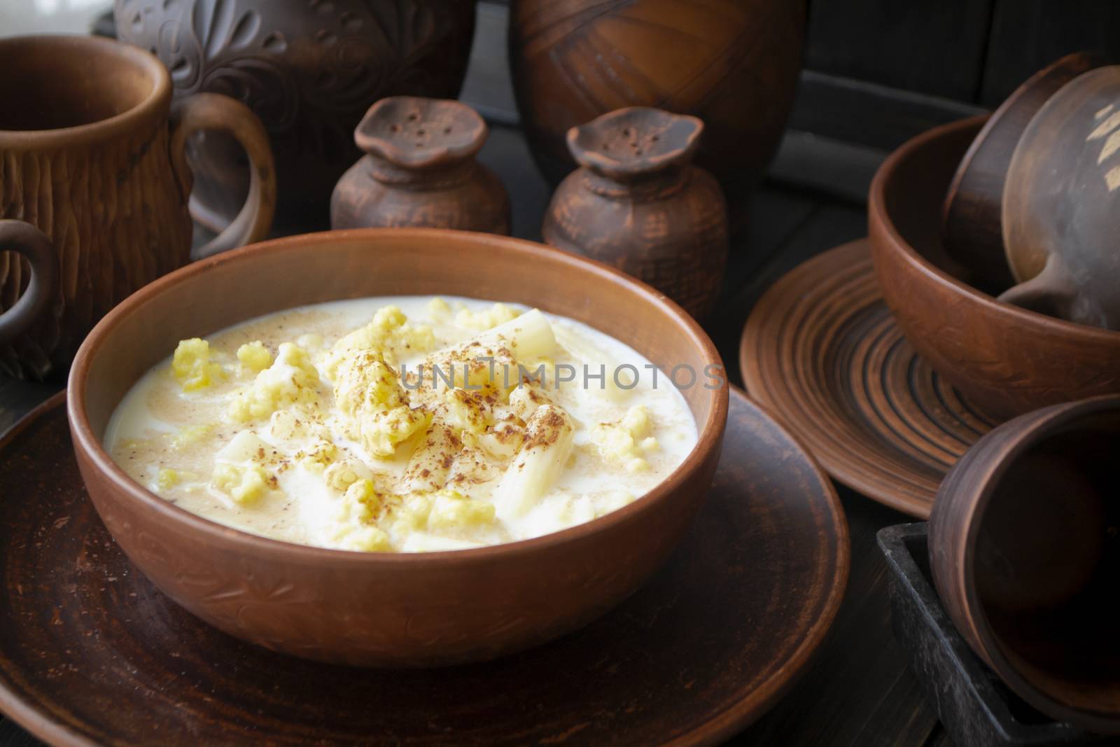 Milk soup with cocoa powder in an old ceramic bowl, dark background