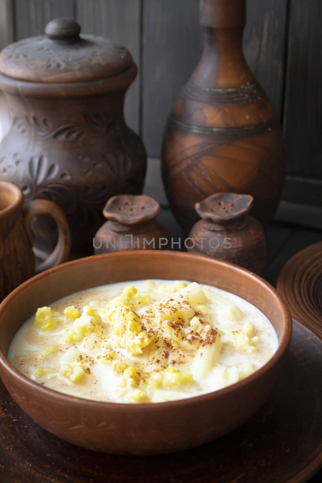 an old ceramic bowl with milk soup on a dark background. Vertical image