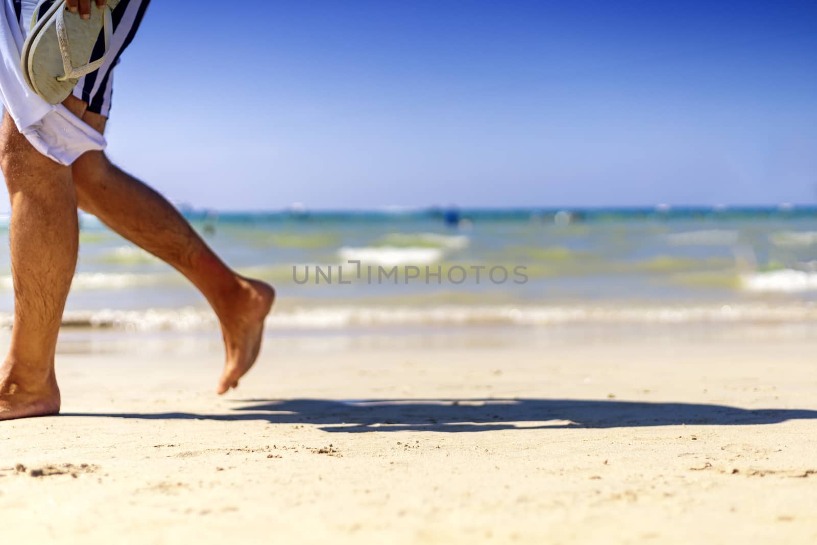 Summer Holiday concept. Clear sand with blur guy, sea and clear sky background. Soft focus and focus selective sand.