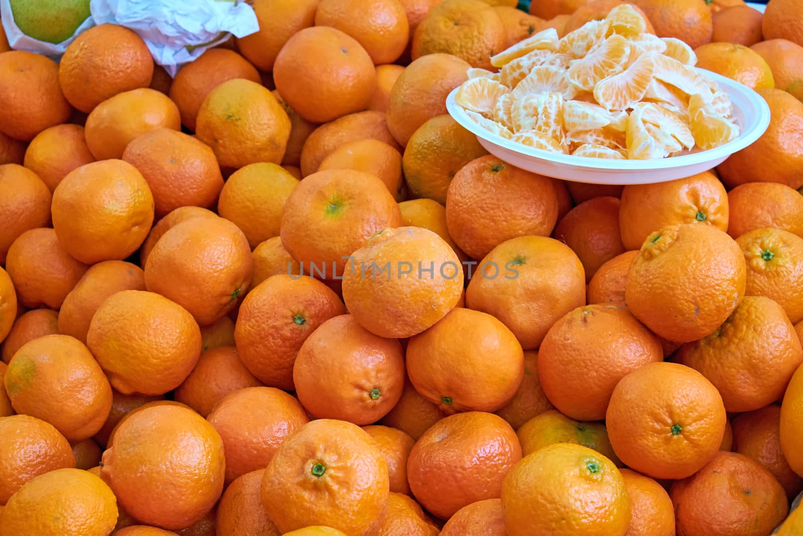 Tangerines for sale at a market with some pieces on a plate