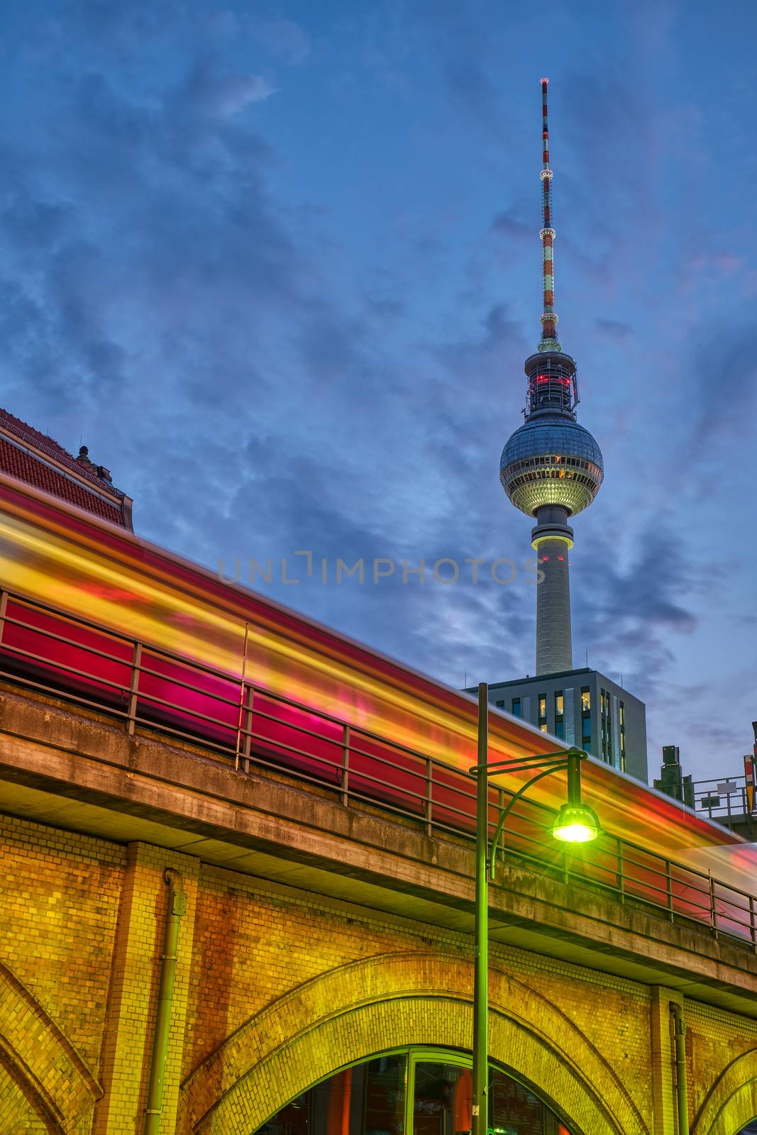 The famous Television Tower in Berlin at dusk with a motion blurred commuter train