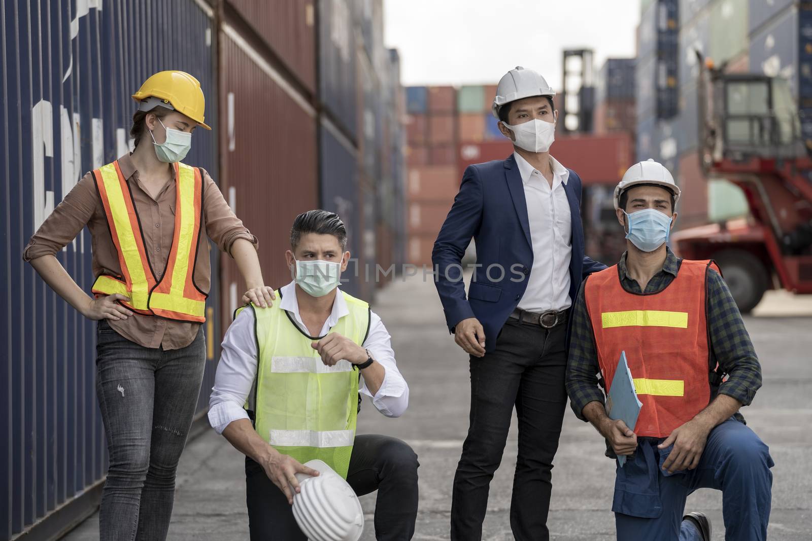 group people worker is wearing protection mask face and safety helmet and wearing suit safety dress With background of container cargo warehouse. Concept of industry worker operating.