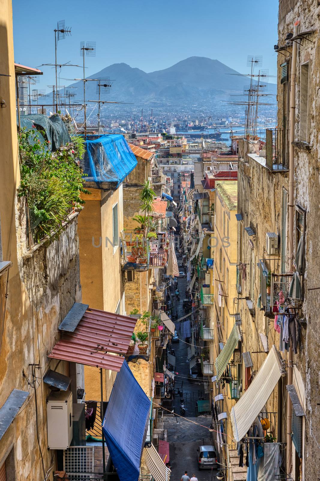 Narrow alleyway in the old town of Naples with Mount Vesuvius in the back