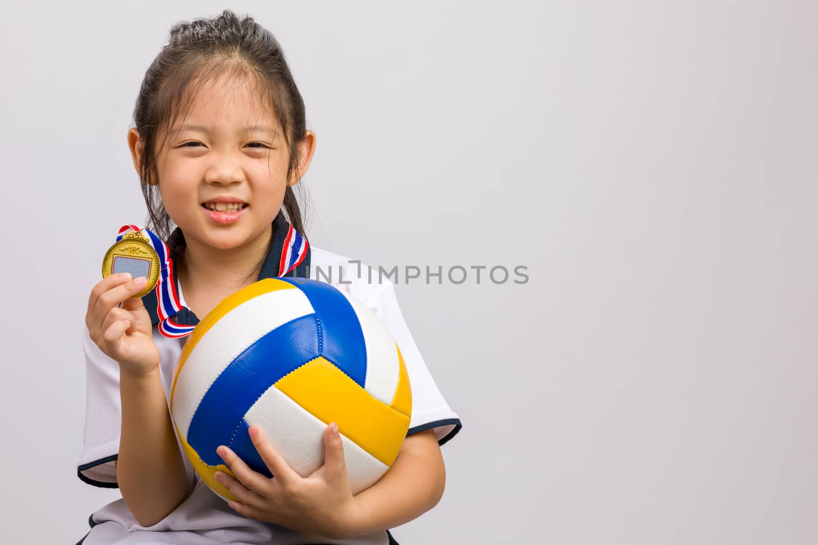 Kid holding ball and gold medal, studio shot, isolated on white.