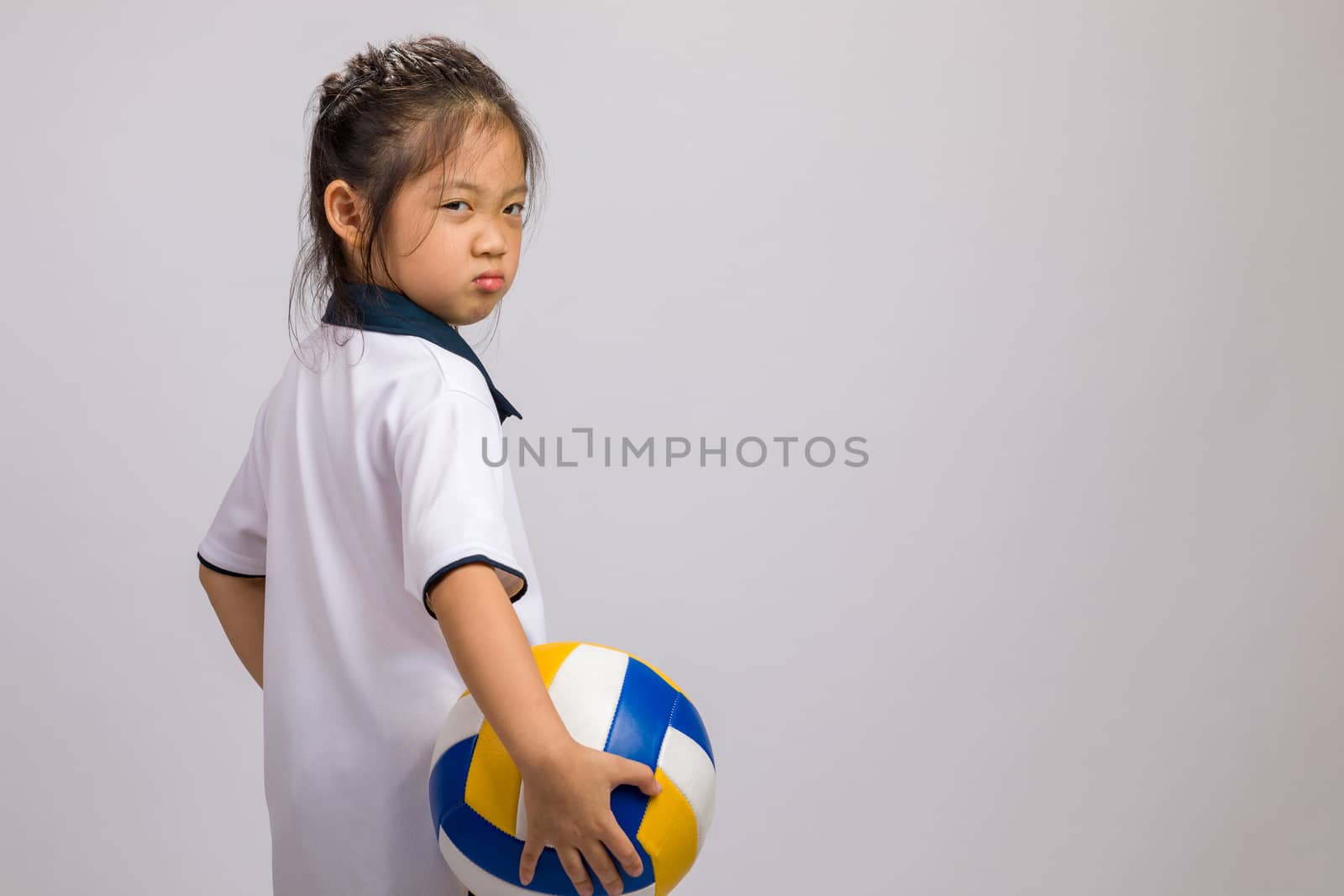 Child holding volleyball, studio shot, isolated on white.