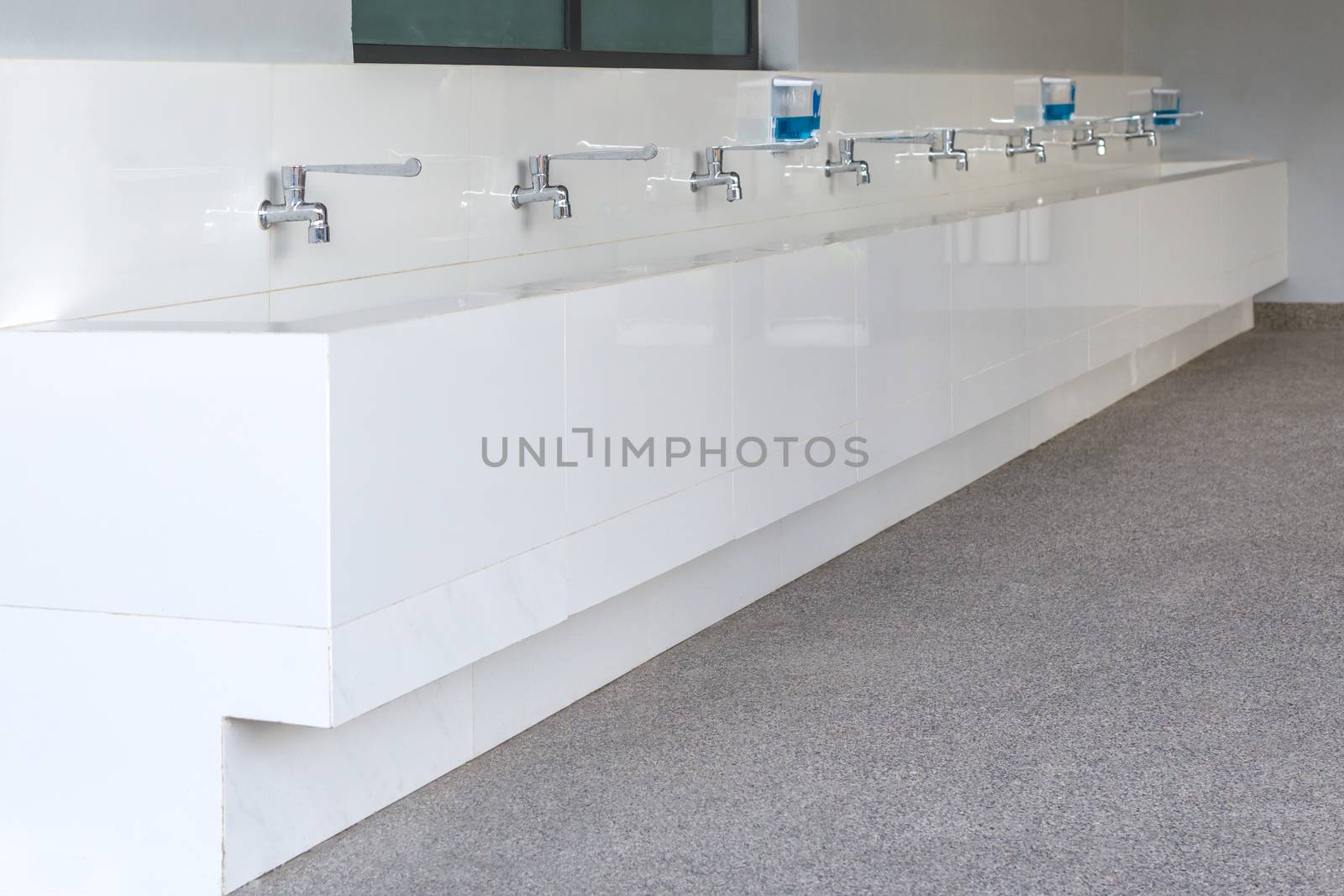 Long row of water tap and sink in school.
