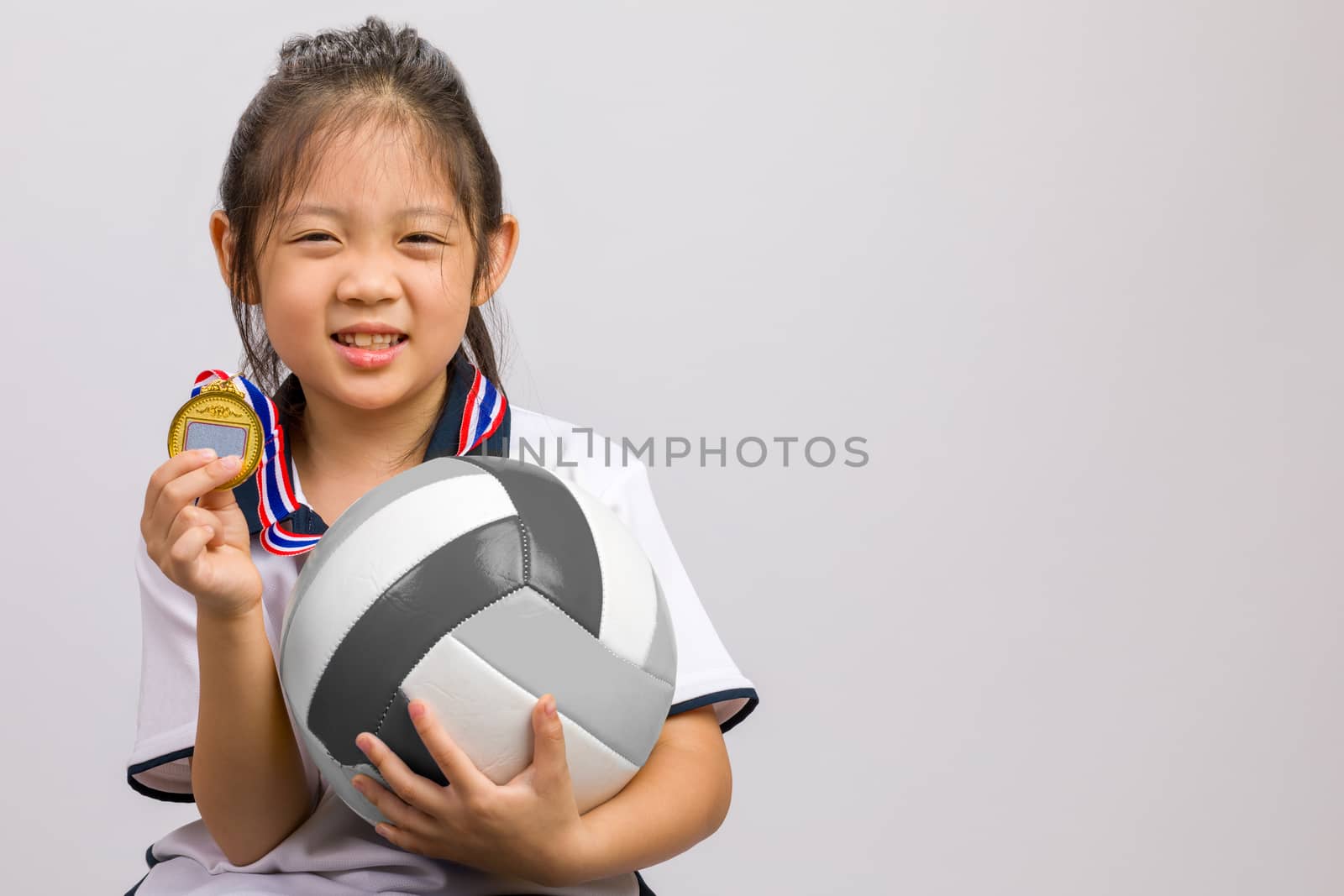 Kid holding ball and gold medal, studio shot, isolated on white.
