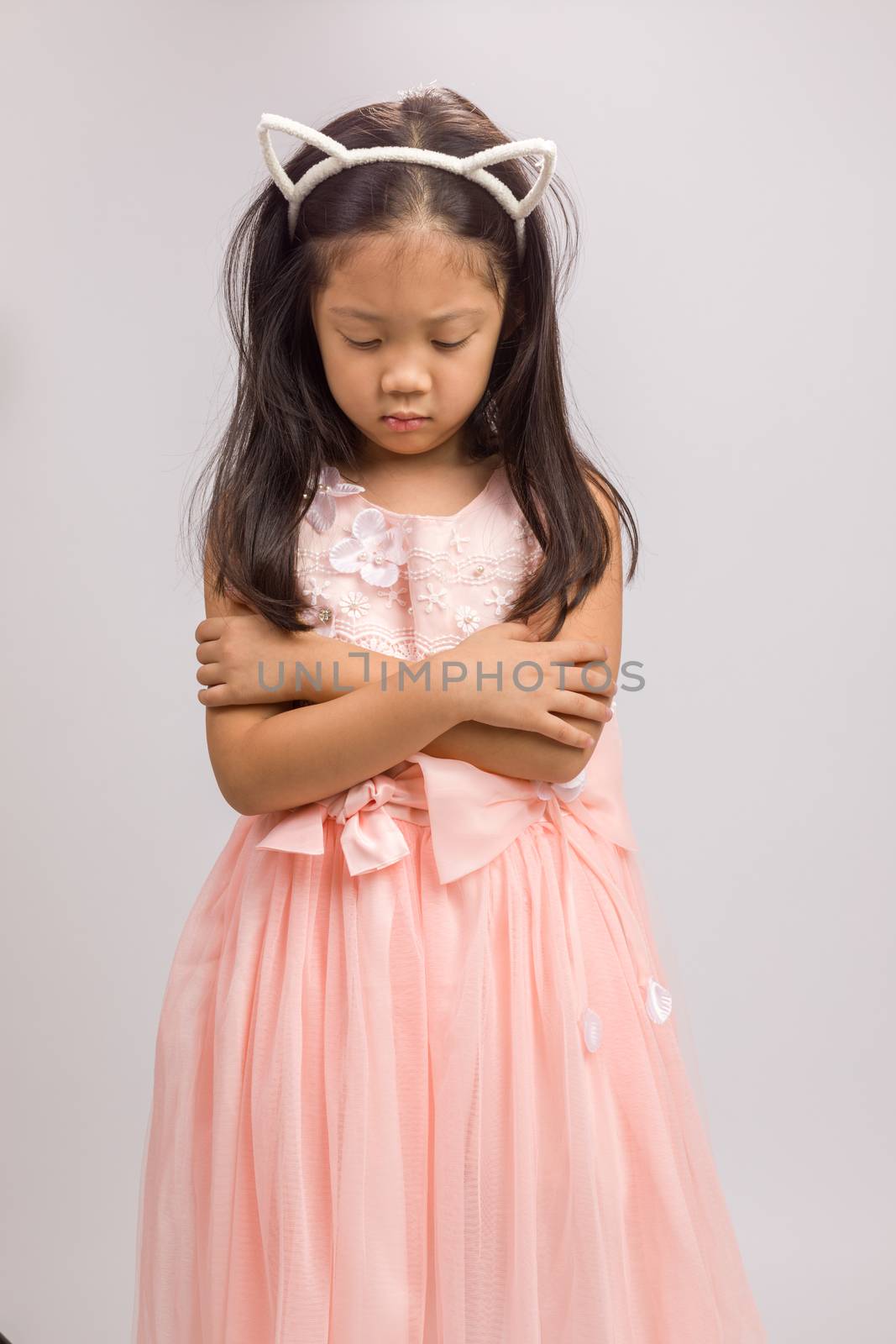 Kid with cat ear headband in pink dress, isolated on white background.