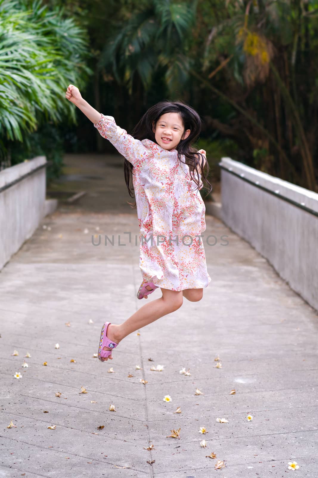 Asian kid jumping with fun and happiness outdoor park.