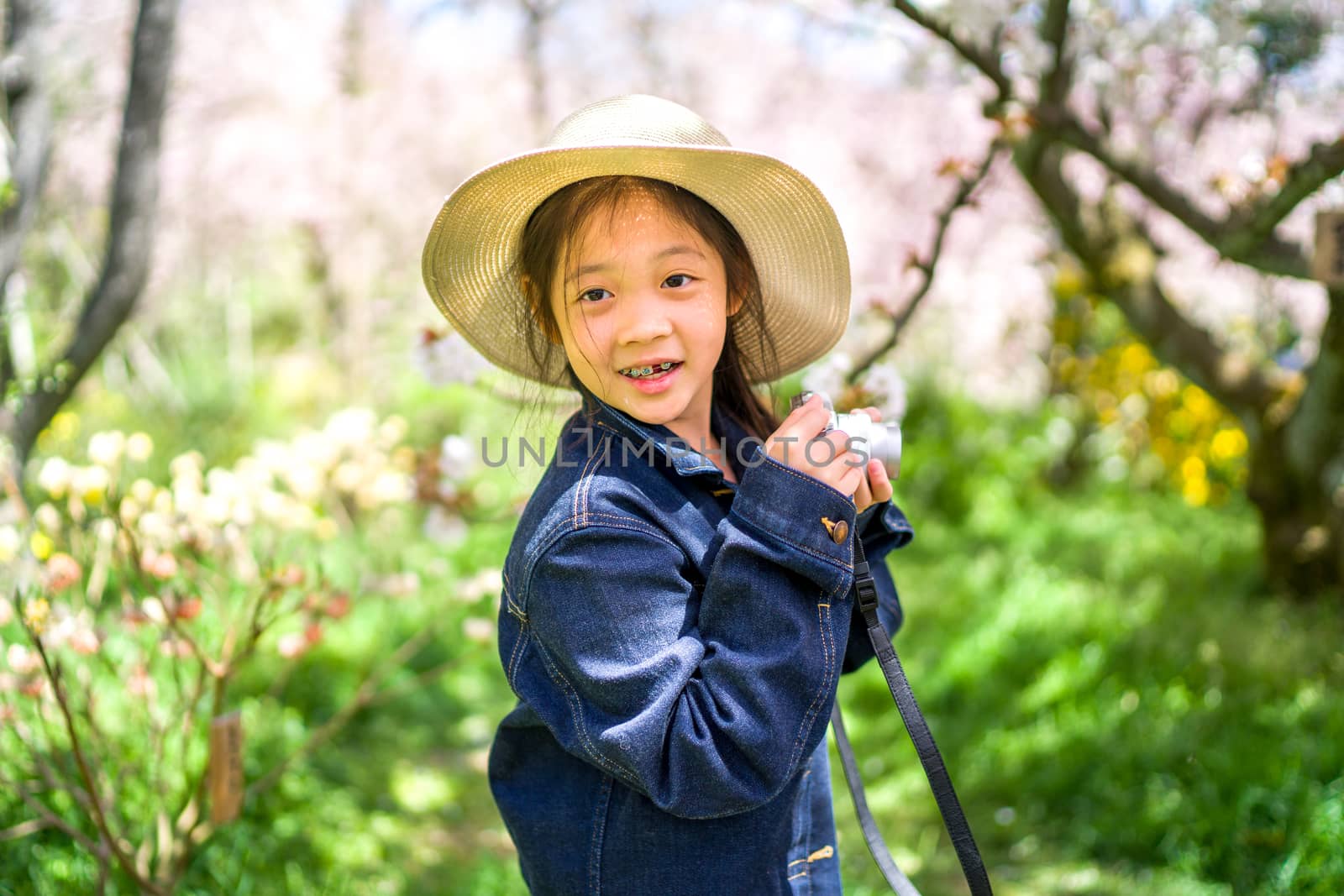 Little Asian girl on her travelling trip for vacation holding camera to take photo.